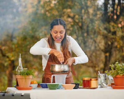 Chef Ivana Sanshia seasoning a pot at an outdoor table