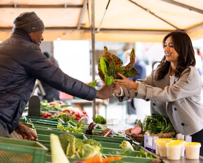 Chef Ivana Sanshia taking a head of lettuce from a market trader